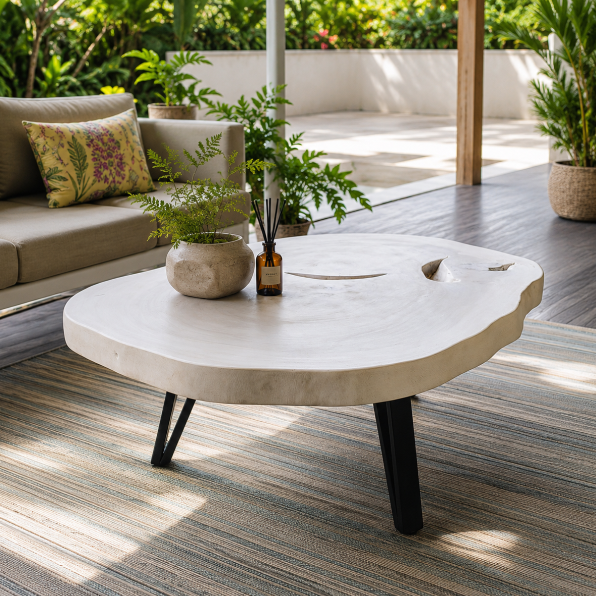 Round stone coffee table with decorative items on a patio.