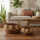 Two hand-woven baskets with pom-pom accents.