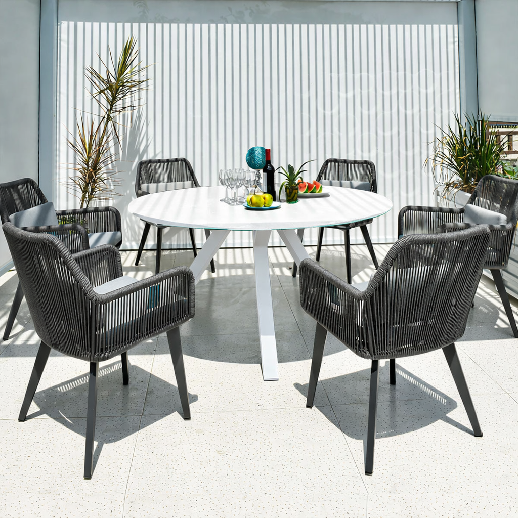Outdoor dining setup with a round table and chairs on a patio.